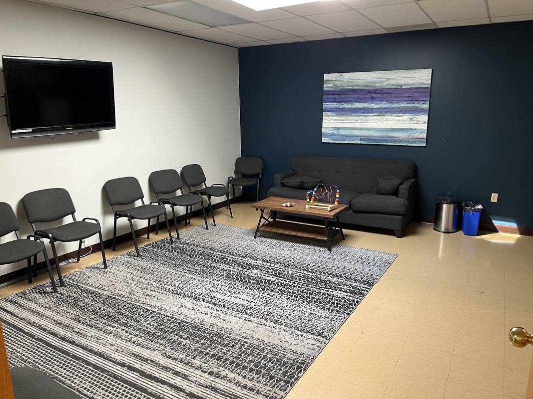 The waiting room at the Burlington office, with chairs, a sofa and a rug