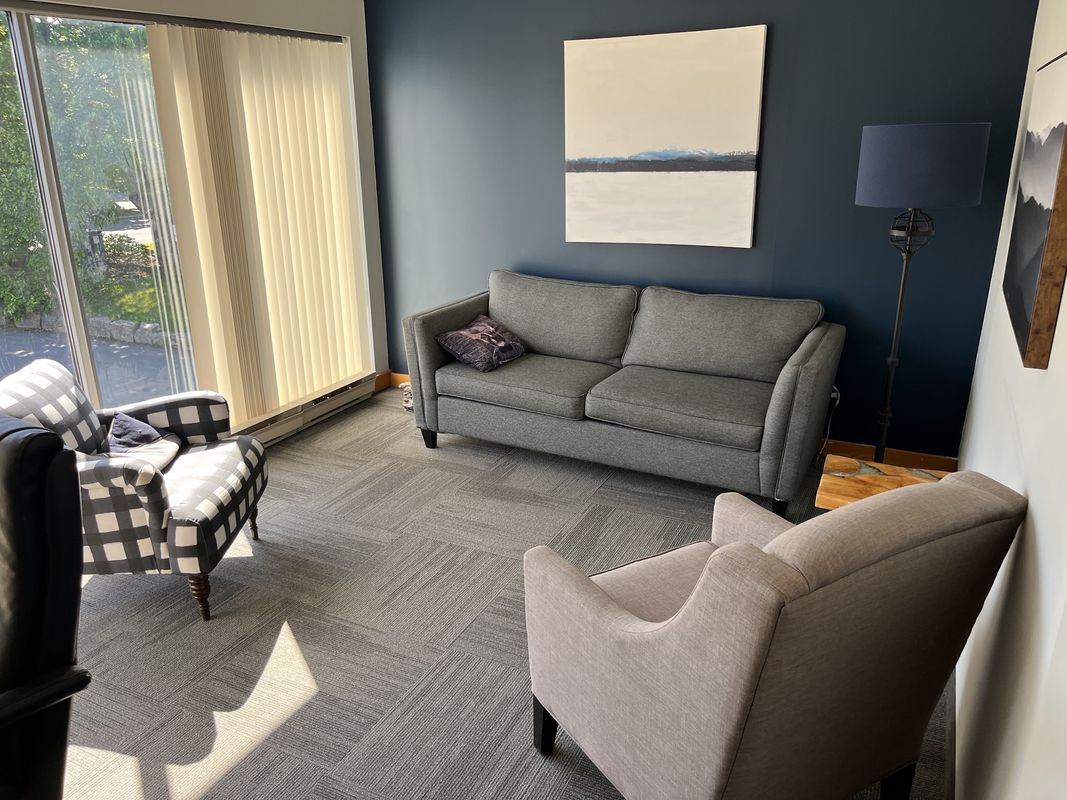 A therapy room at the Burlington office, with a sofa, two armchairs and a tall window